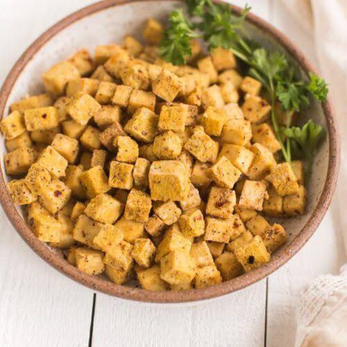 Bowl of tofu croutons for soup made in the air fryer, garnished with fresh parsley.