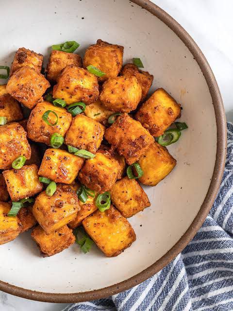 Fried tofu croutons for soup made in the air fryer, served with vegetables in a bowl.