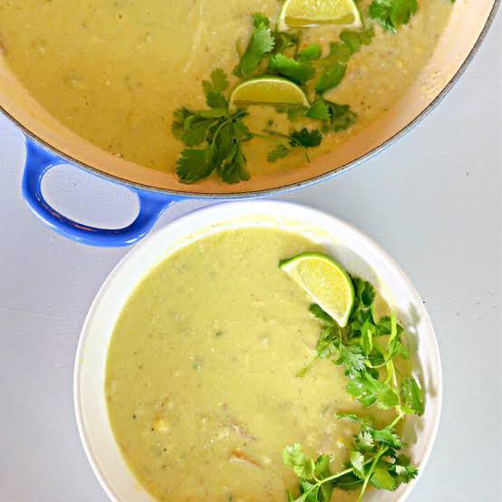 Serving cream of jalapeno soup with cilantro, sliced lemon, and sour cream for texture, in a blue-handled pot.