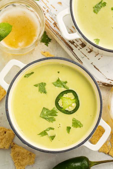 Pots containing hot soup freshly served with sliced jalapenos, cilantro, and other spices for a balanced flavor.