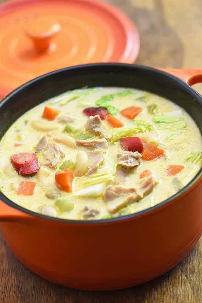 A freshly served hot soup in an orange bowl.