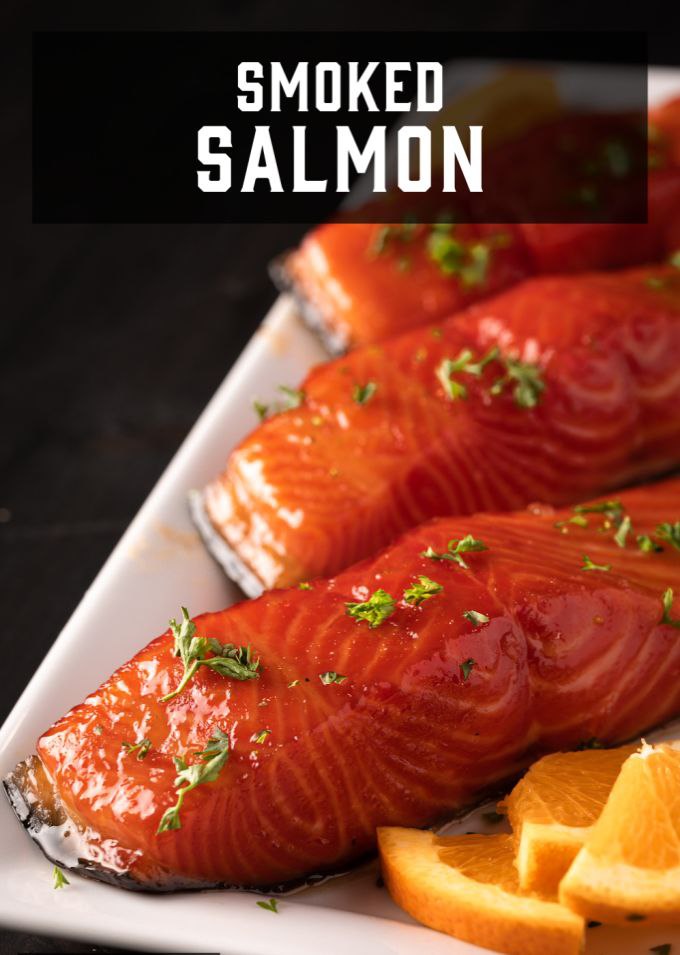 Smoked salmon served with lemon slices on a white plate.